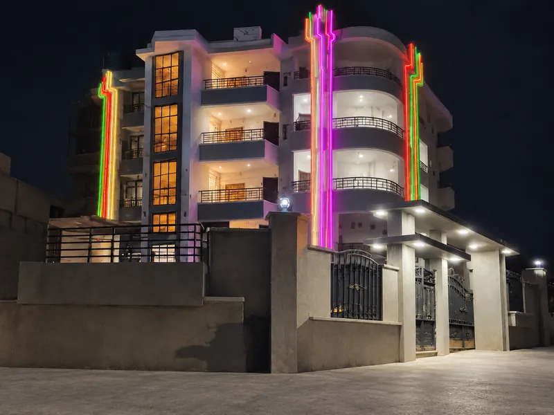 Night view of a multistorey building with illuminated balconies and multicolour light strips.