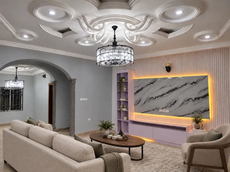 Living room with a cream sofa, an armchair, a walnut coffee table and a rug beneath a crystal chandelier.